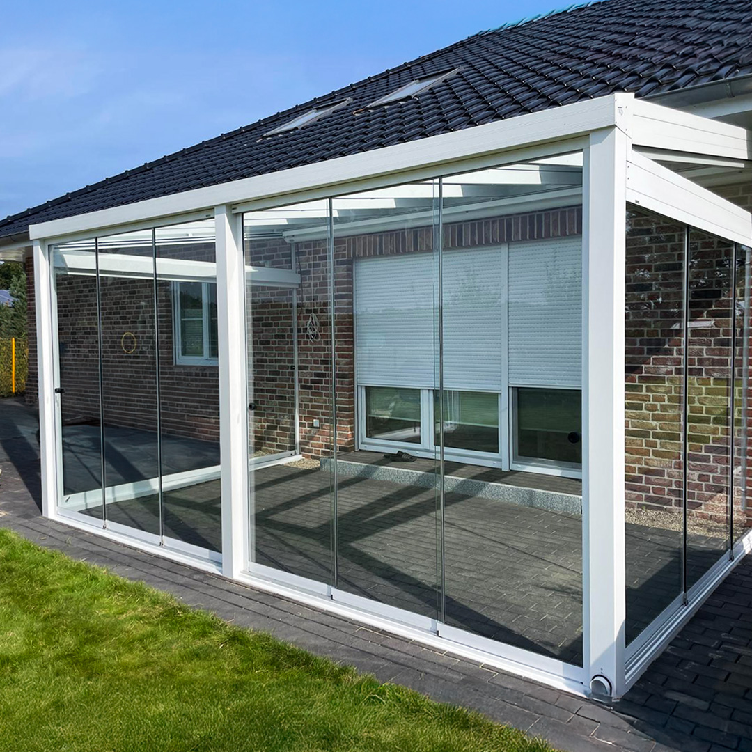 Weißer Sommergarten mit transparenten Glas-Schiebeelementen