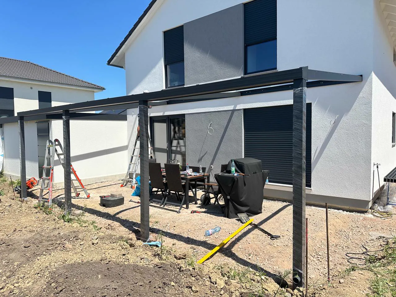 Aluminiumkonstruktion einer anthrazitfarbenen Terrassenüberdachung während der Montage