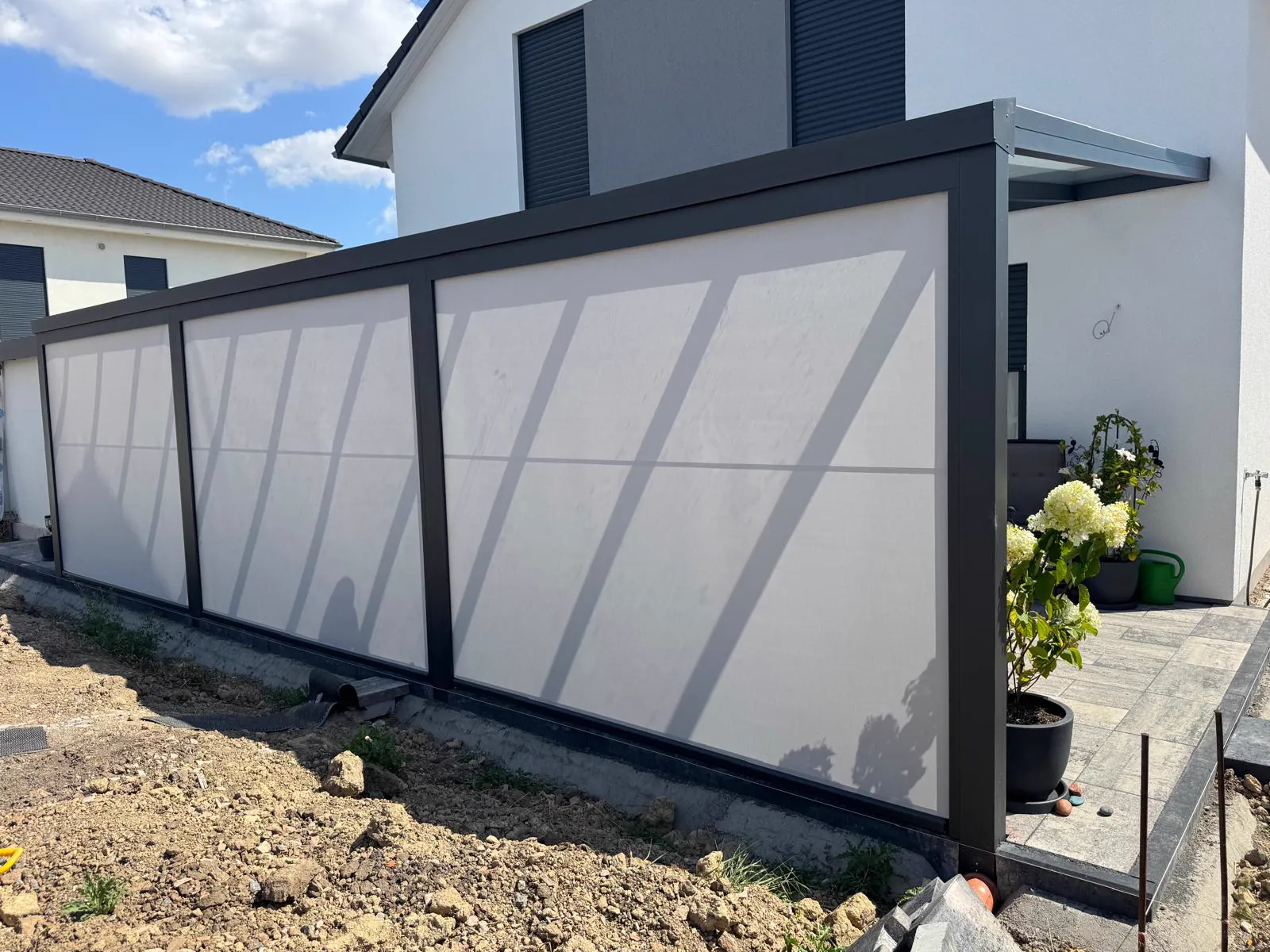 Anthrazitfarbene Terrassenüberdachung mit großflächigen hellen Seitenelementen